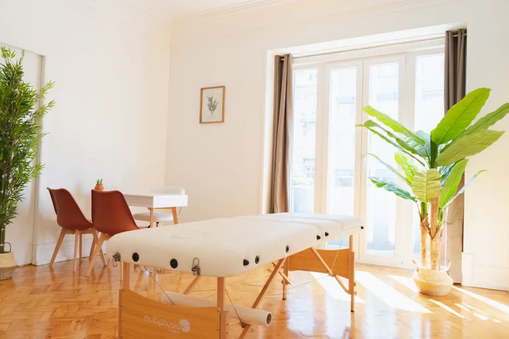 Sala para terapias em Lisboa com marquesa, mesa e plantas, no Saldanha