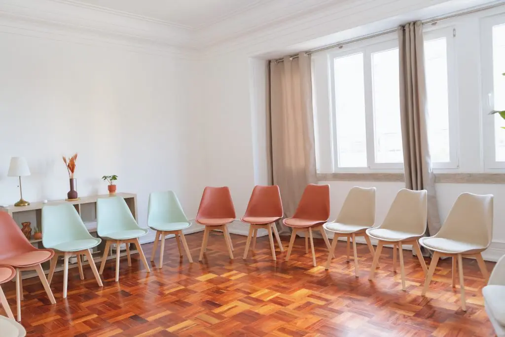 Sala com filas de cadeiras terracota e verde-água para eventos em Lisboa
